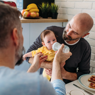 Two men sitting and baby in safe hands