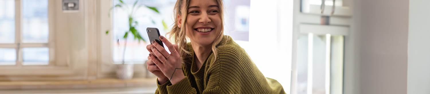 A person looking away from their phone smiling