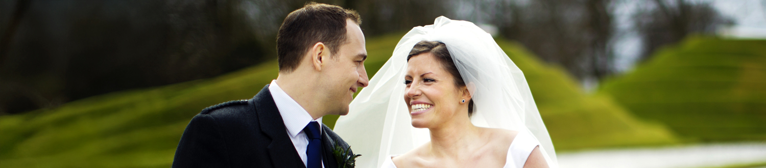 A bride and a person in a suit smiling at each other