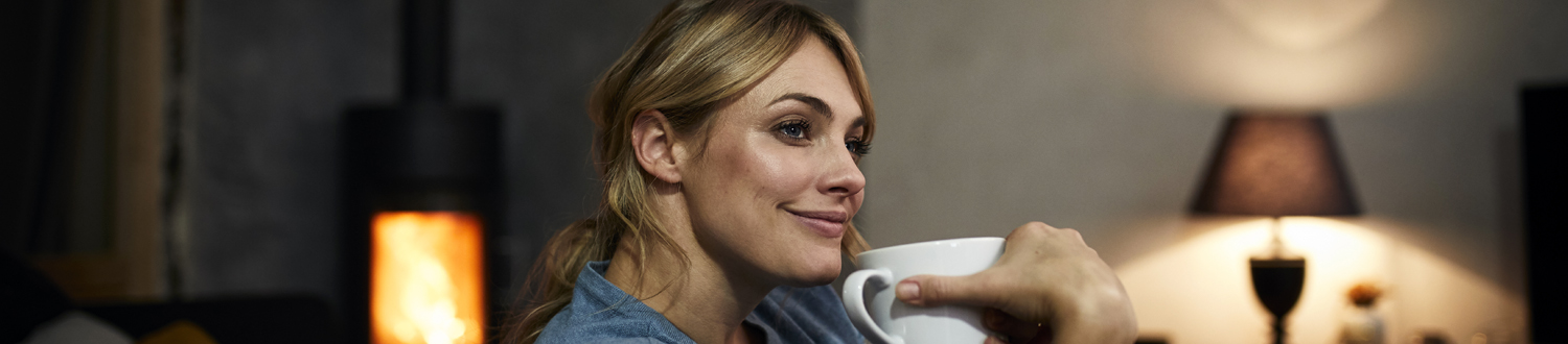 A person sat down smiling holding a mug up to their face