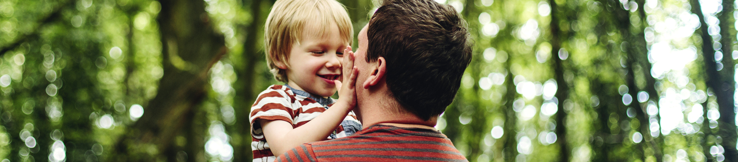 An adult holding a child face to face outside