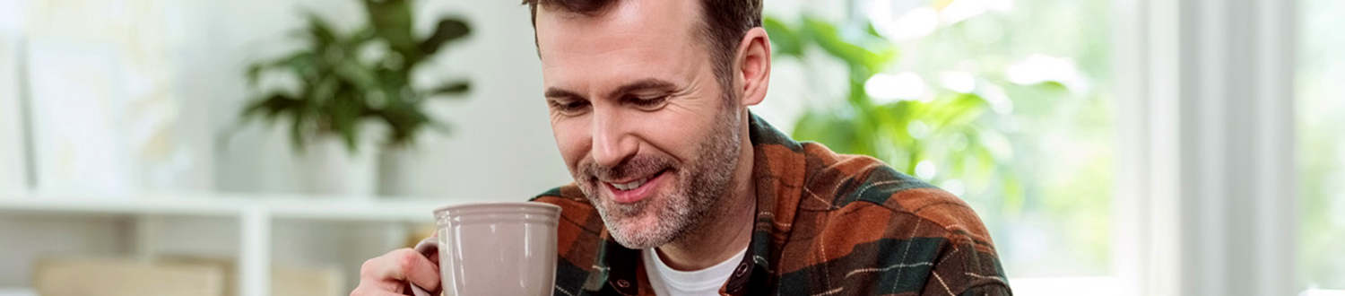 A person holding a mug and looking down smiling