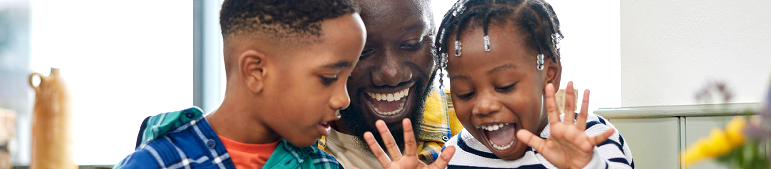 A person and two children smiling looking down at something