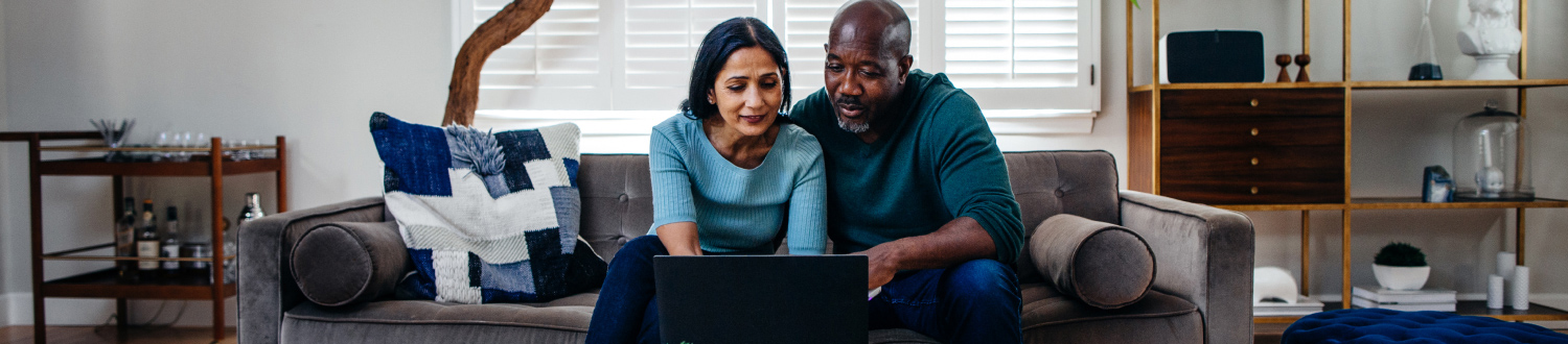 Two people sat on a sofa looking at a laptop
