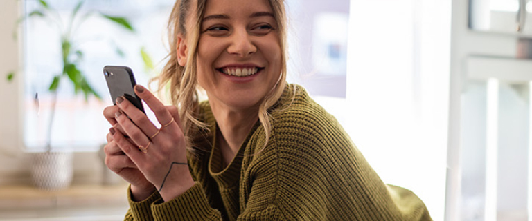 A person looking away from their phone smiling