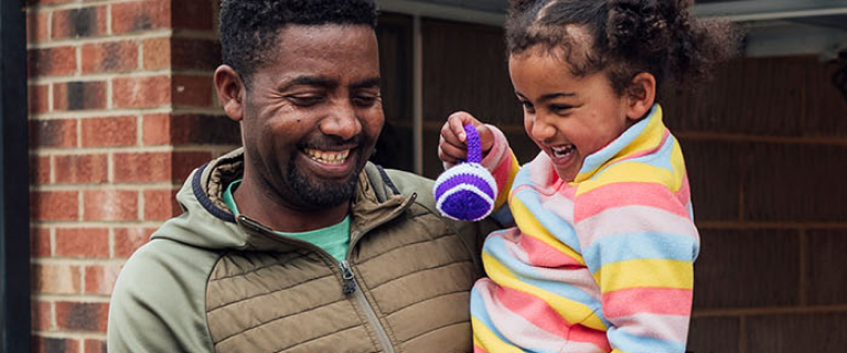 An adult carrying a child, both laughing