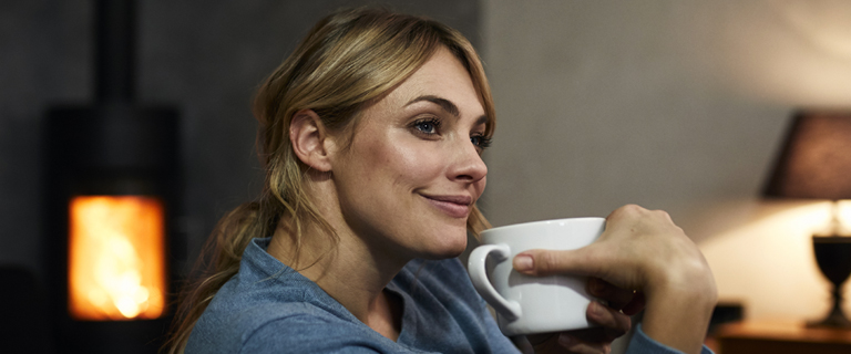 A person sat down smiling holding a mug up to their face