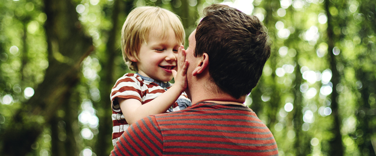 An adult holding a child face to face outside