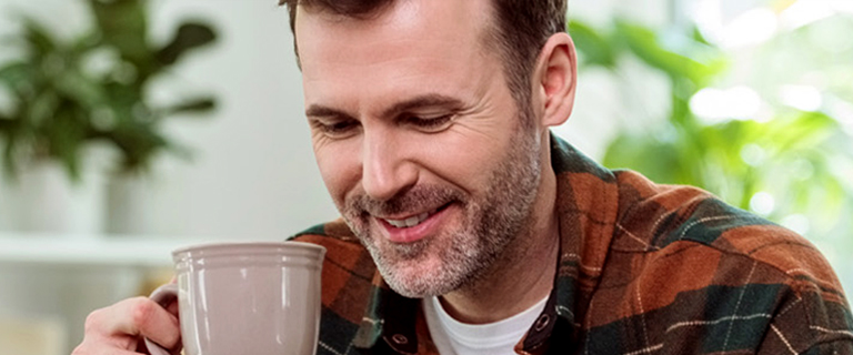 A person holding a mug and looking down smiling