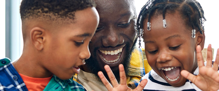 A person and two children smiling looking down at something