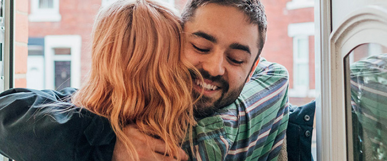 Two people hugging at the front door of a house