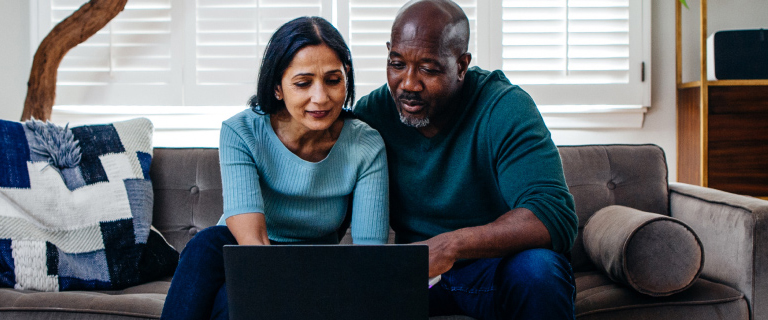 Two people sat on a sofa looking at a laptop
