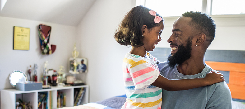 Adult holding child as they smile at each other