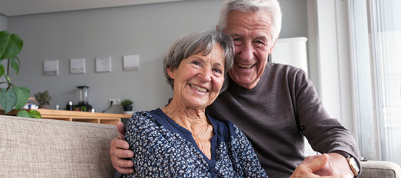 Two people sat on sofa smiling