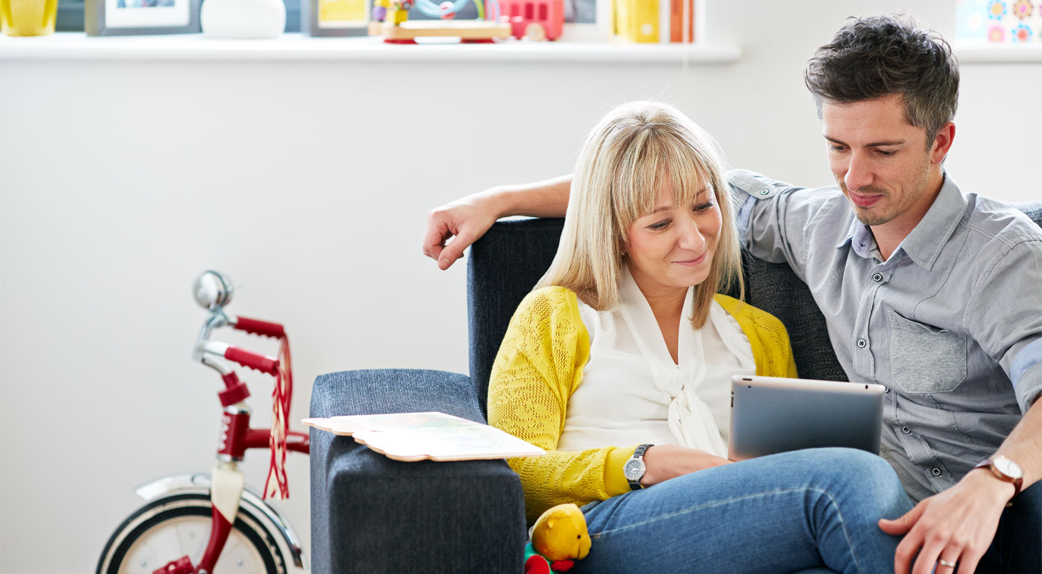 woman and man looking at tablet whilst sat on sofa