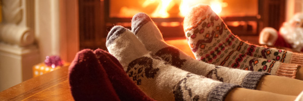 people wearing socks with their feet up in front of a roaring fireplace