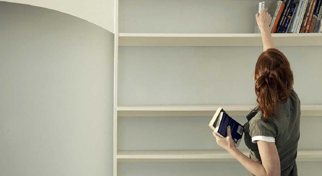 woman putting books on a bookcase