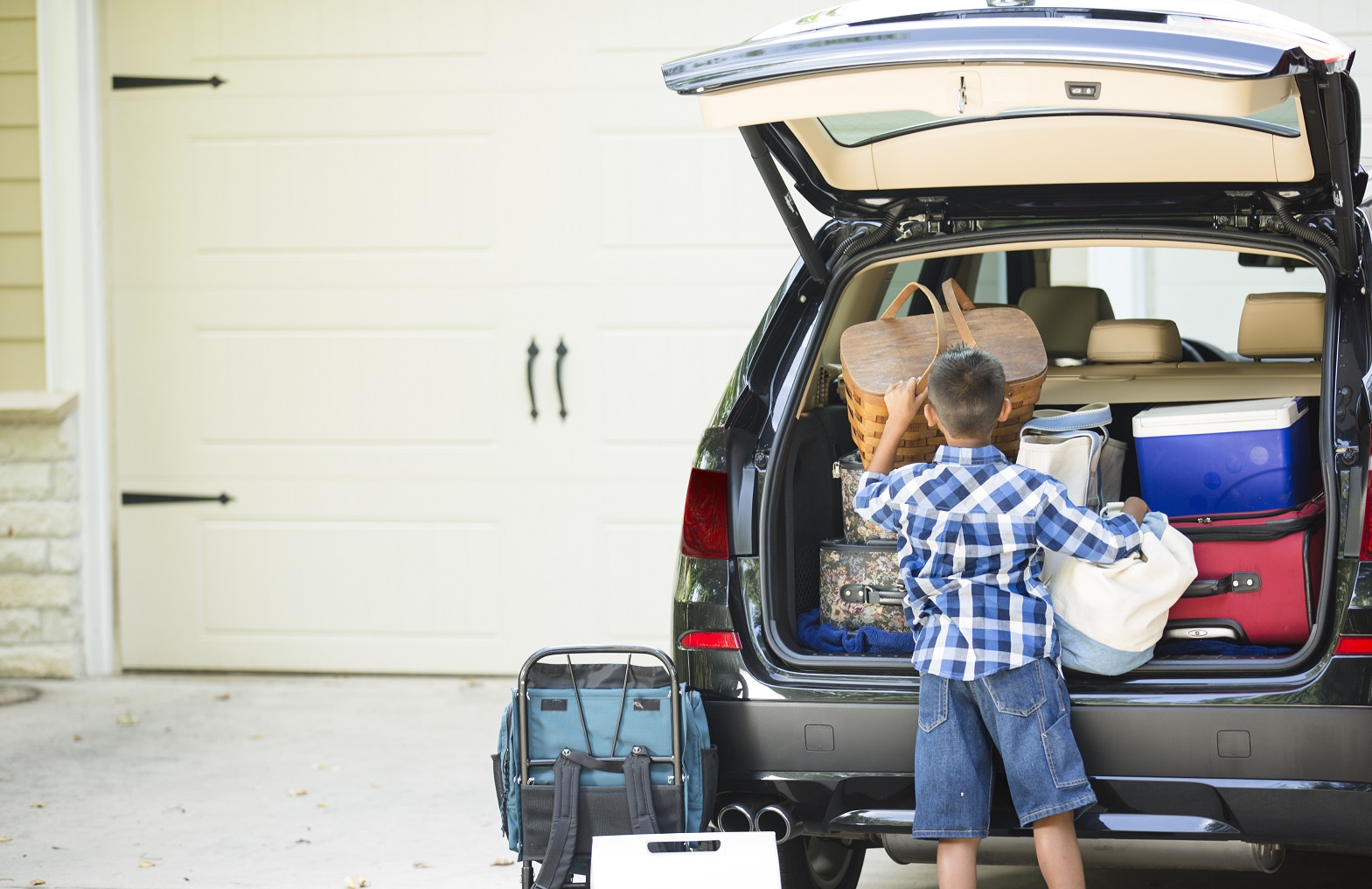 child packing a basket into the back of a car