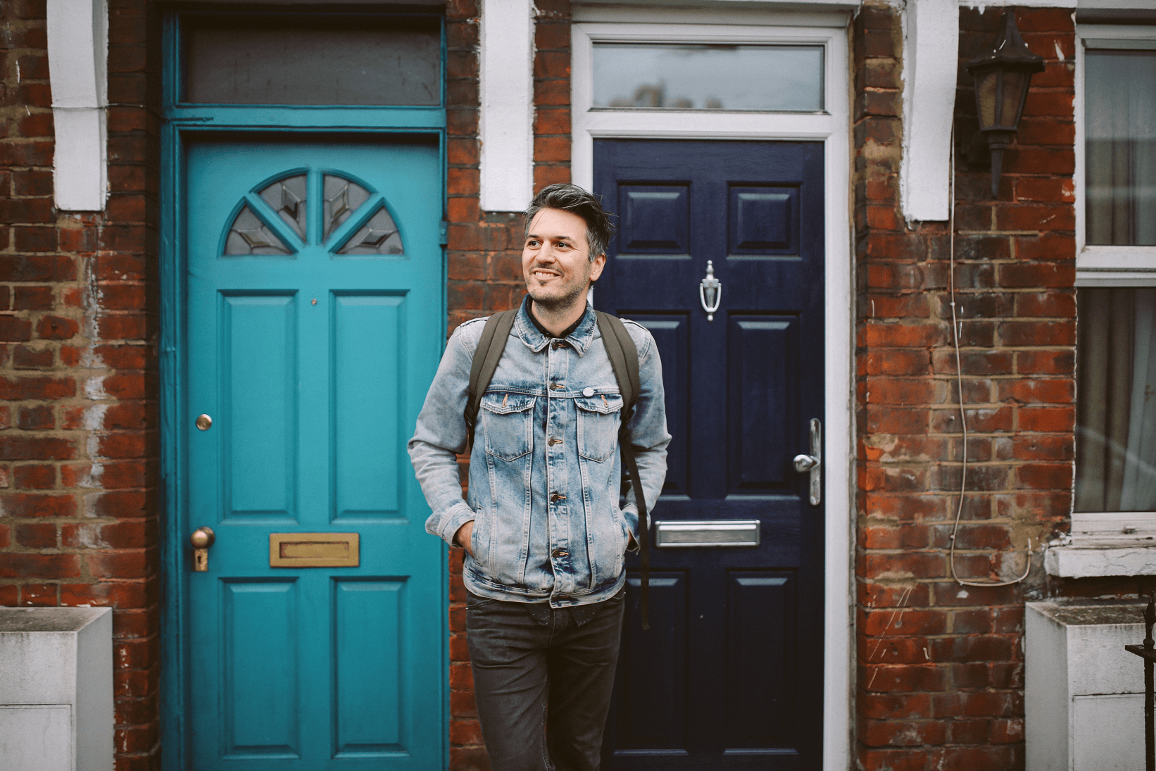 man in front of house with blue door