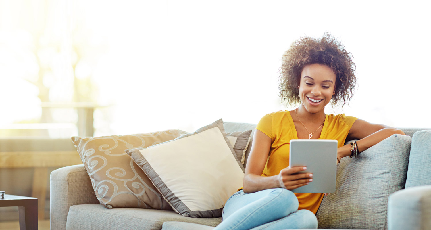 A person sat down smiling at an electronic tablet