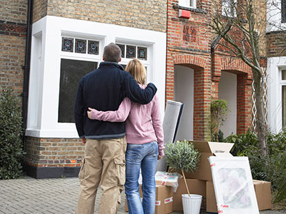 Two people hugging and looking at house