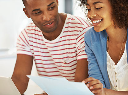 Two people smiling looking at pieces of paper