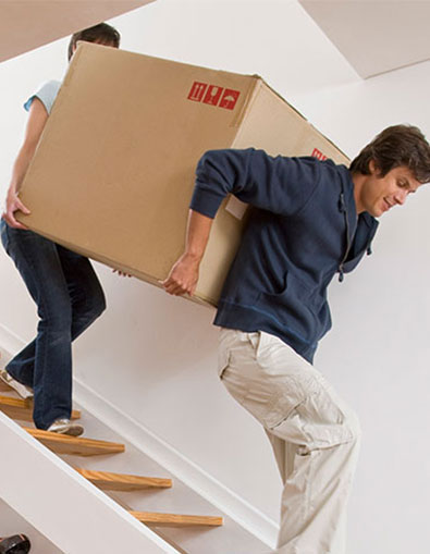 man and woman moving large box downstairs