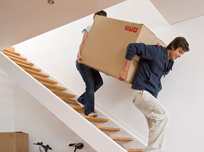 man and woman moving box downstairs