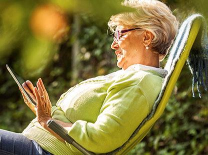 woman reading tablet whilst sat in deckchair in garden