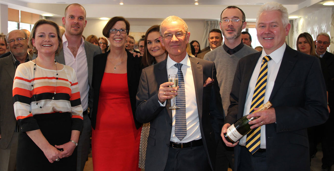 John Manship holding a glass of champagne surrounded his Leeds Building Society colleagues