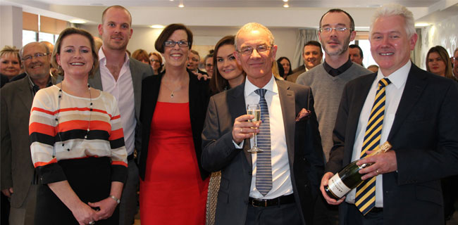 John Manship holding a glass of champagne surrounded his Leeds Building Society colleagues