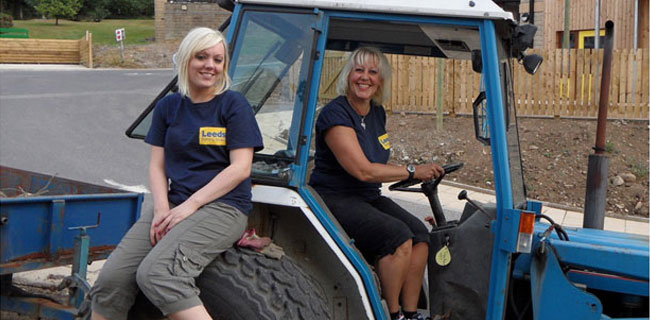A photo of two women sat in a tractor
