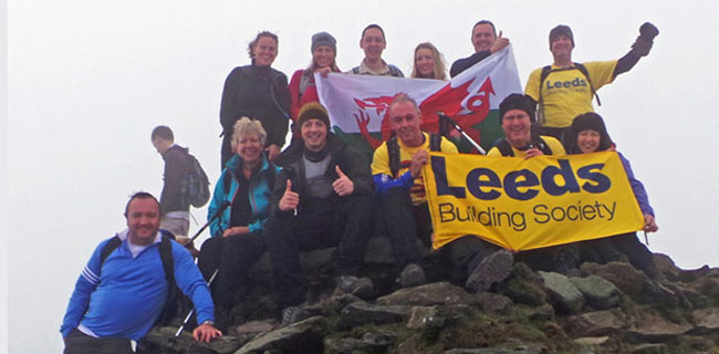A group of people at the top of a mountain with a Leeds Building Society banner