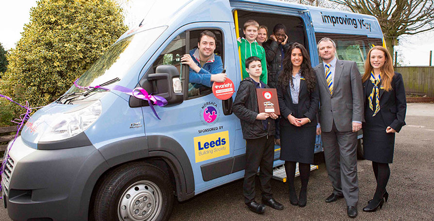 Jason Manford and members of Leeds Building Society presenting a bespoke bus to pupils from Sutherland House School