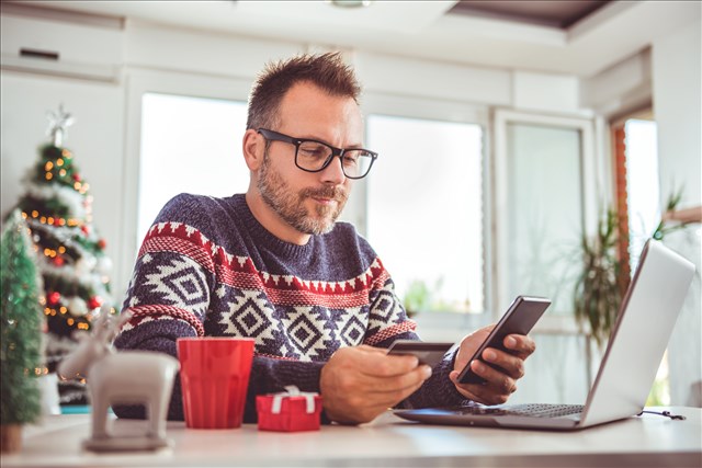 man in christmas jumper using credit card to pay an online payment