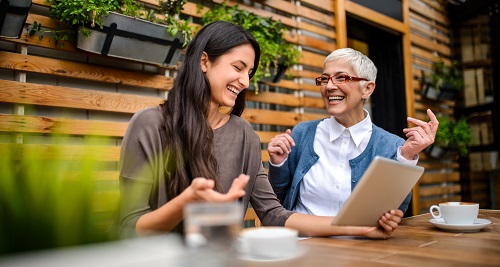 2 women talking and looking at a tablet in a cafe